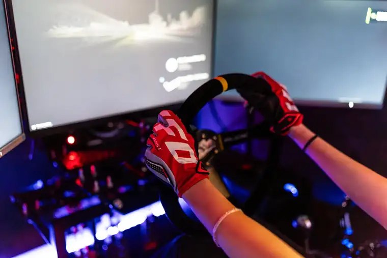 Ruky v pretekárskych rukaviciach na volante simulátora